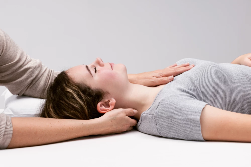 Craniosacraltherapeutin behandelt Klienten an Nacken und Brust